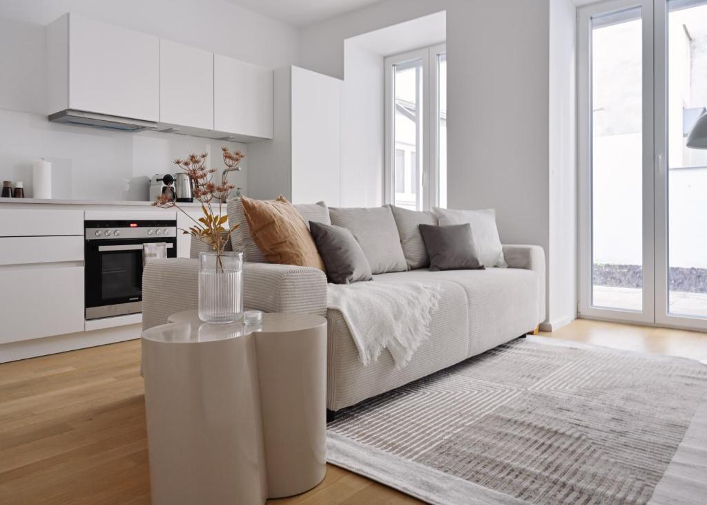 a white living room with a couch and a table at Stylish & Modern Apartment - Private Garden & Free Parking in Vienna