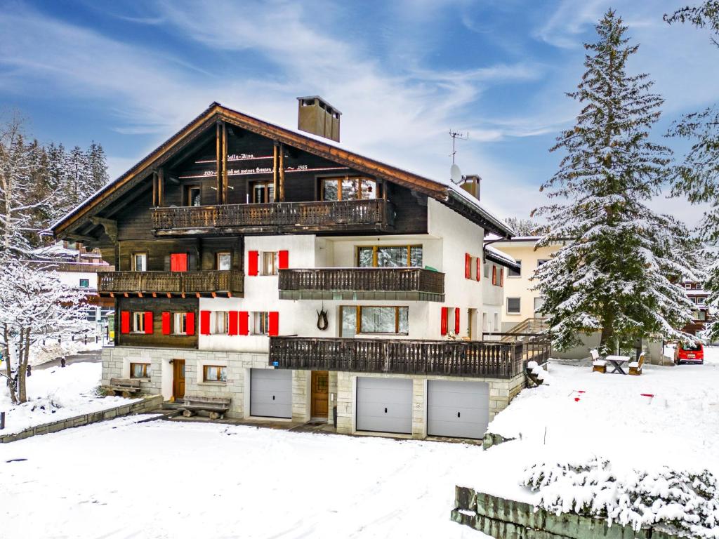 een groot huis met rode en witte deuren in de sneeuw bij Bella Riva by Arosa Holiday in Arosa