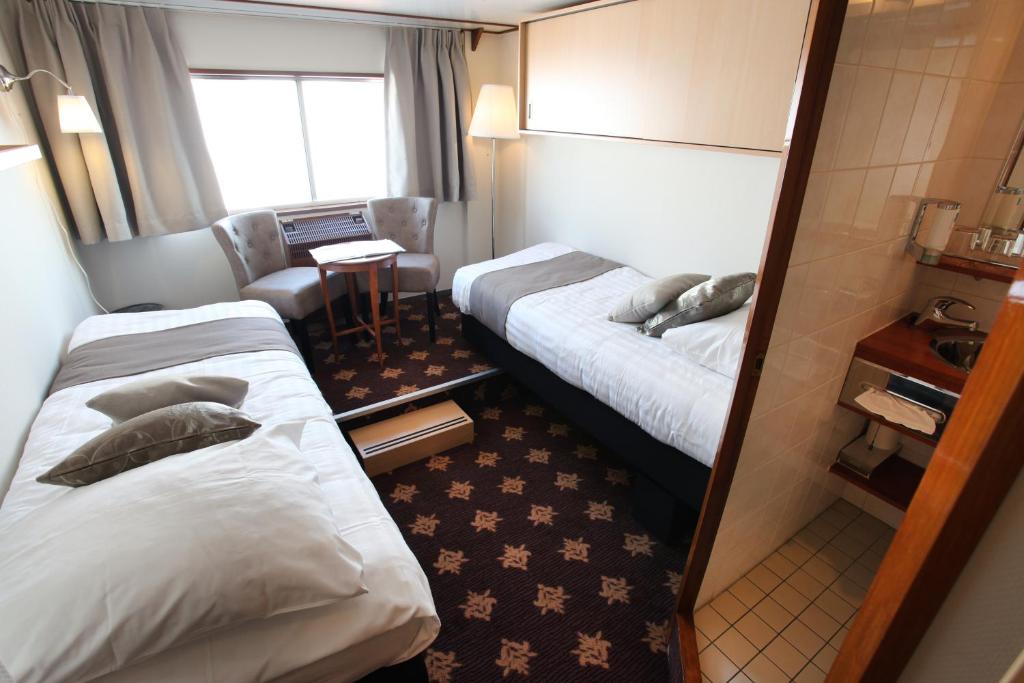 ein Hotelzimmer mit 2 Betten und einem Stuhl in der Unterkunft Fairtours Hotelschiff Rex Rheni *** in Düsseldorf
