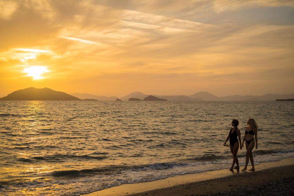 Dos mujeres caminando por la playa al atardecer en Sunset Beach Villas and Apartments, en Fethiye