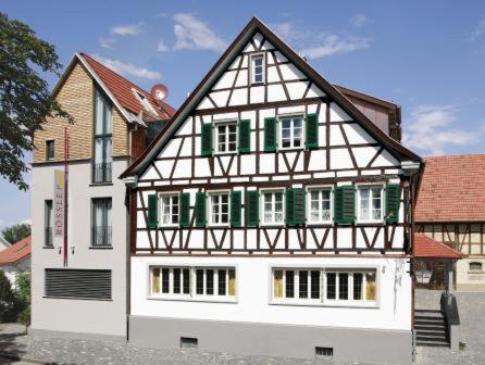 Ein weißes und grünes Haus, auf dem ein Mann steht. in der Unterkunft Gasthaus Rössle in Kirchheim unter Teck