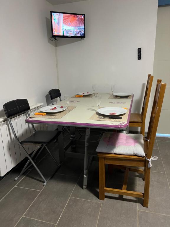a table with chairs and plates and a tv on a wall at Très bel Appartement bleu in Montclar