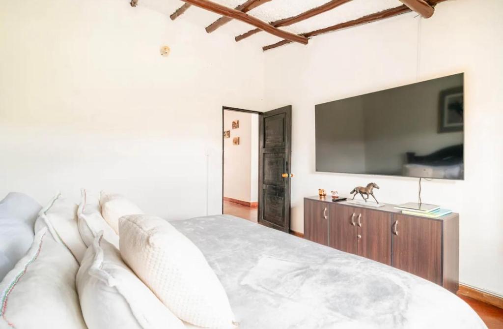 a bedroom with a large white bed and a tv at HERMOSA CASA CAMPESTRE 