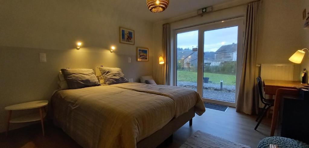 a bedroom with a bed and a large window at B&B Les Lits de Nohaipré in Rendeux