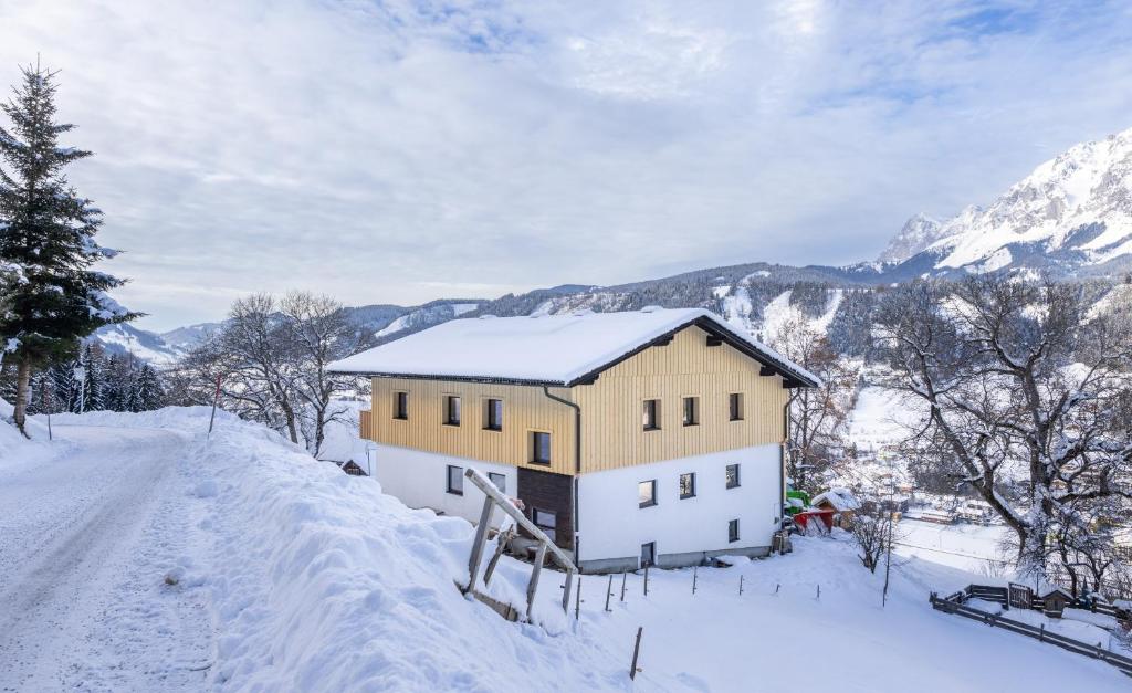 een huis op een besneeuwde heuvel met bergen op de achtergrond bij Appartements Uribi mit eigener Sauna by Schladmingurlaub in Schladming