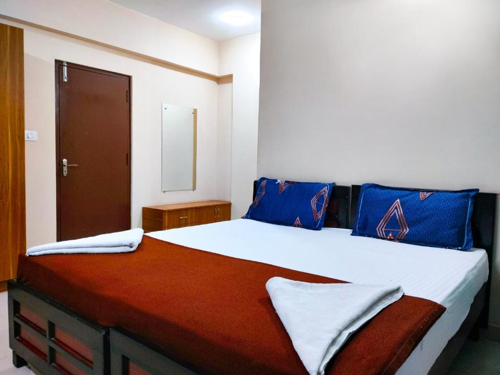 1 dormitorio con 1 cama grande con almohadas azules en Primera Extended Stay Apartments, en Bangalore