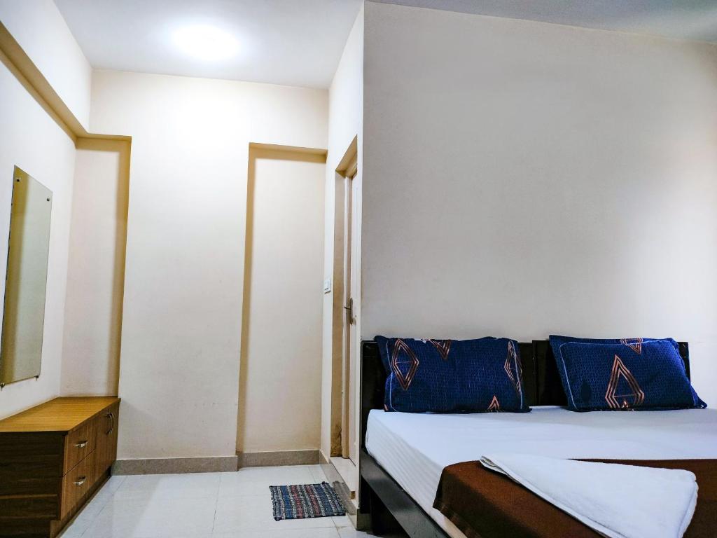 une chambre avec un lit avec des oreillers bleus dans l'établissement Primera Extended Stay Apartments, à Bangalore