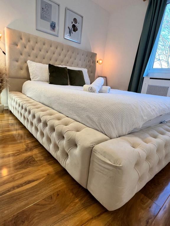 a large white bed with a large tufted headboard at 3-Bedroom Apartment In The Heart of London in London
