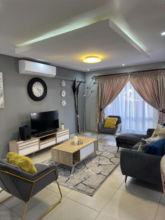a living room with a couch and a tv at Gardens Villa in Nelspruit
