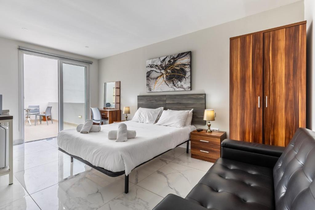 a bedroom with a large bed and a couch at Studio Penthouse with kitchenette and side seaview at the new Olo living in Paceville