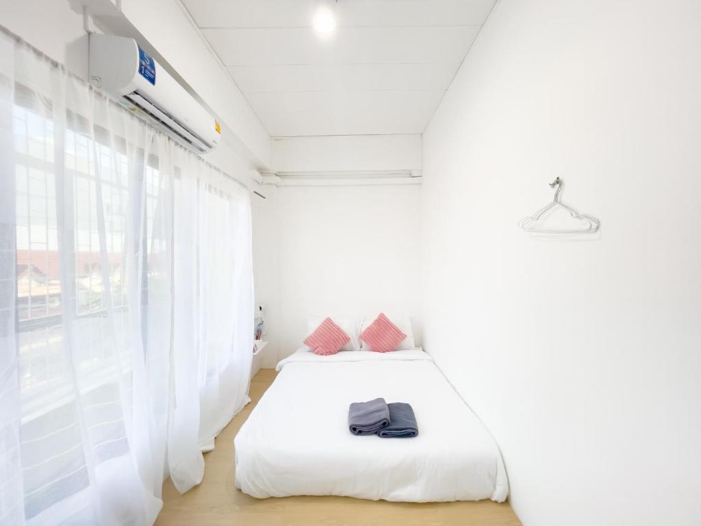 a white bedroom with a bed and a window at TRANSIT Donmueang Airport HOSTEL in Thung Si Kan
