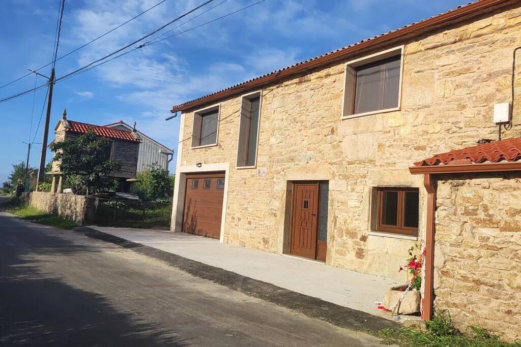 um edifício de tijolos com duas portas de garagem numa rua em Casa Souto em Santa Comba