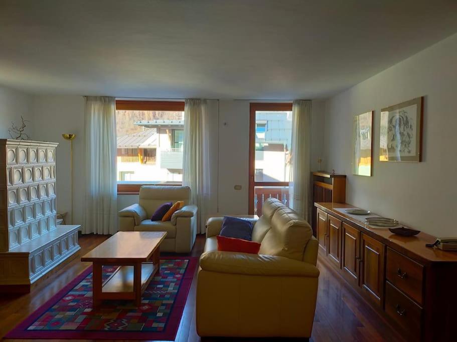 een woonkamer met een bank, stoelen en een tafel bij Spazioso appartamento Nico in Dimaro