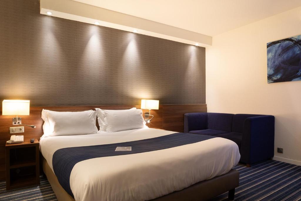 a hotel room with a bed and a blue chair at Holiday Inn Express Amiens, an IHG Hotel in Amiens