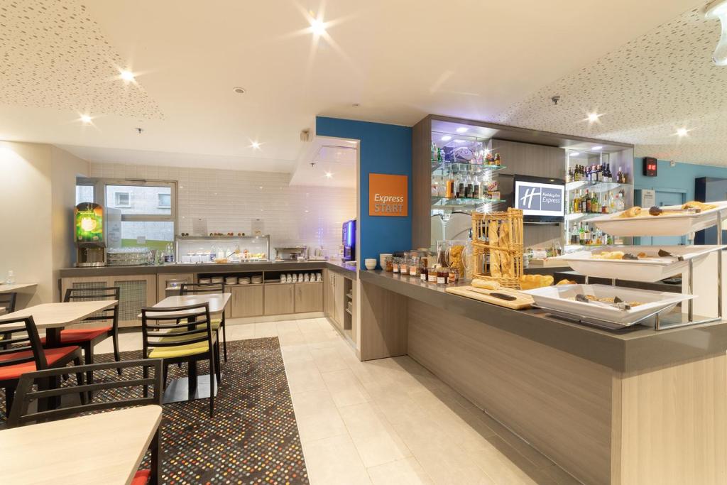 a restaurant with a counter and tables and chairs at Holiday Inn Express Amiens, an IHG Hotel in Amiens