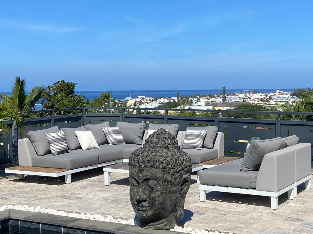 a statue of a head on a patio with couches at Villa L’Eden Zen face à l océan in Saint-Pierre