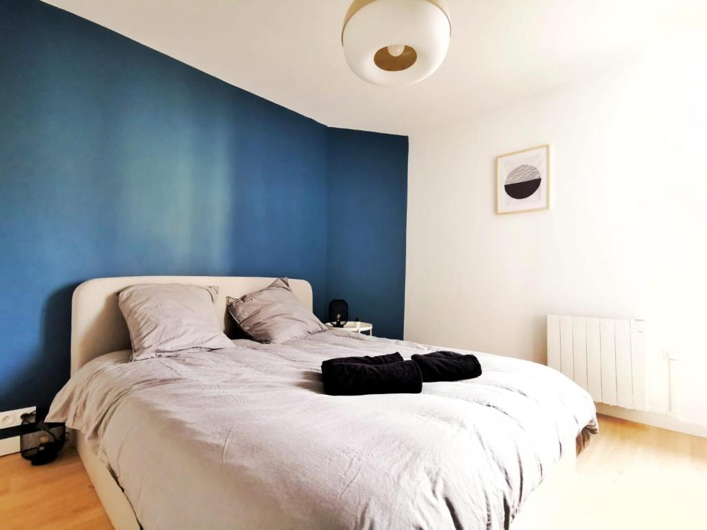 een slaapkamer met een groot bed met een blauwe muur bij Le Contemporain (Centre - Gare - Commerces) in Lens