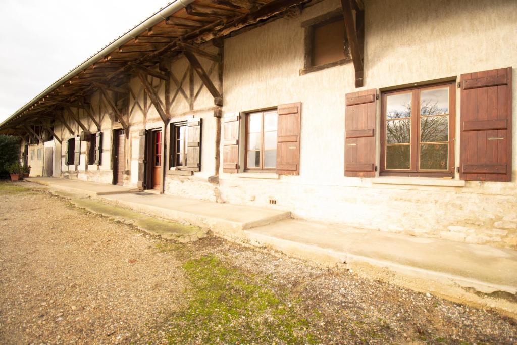 Ferme Bressane - 4 chambres في Saint-Étienne-du-Bois: مبنى قديم شبابيكه وممشى بجانبه