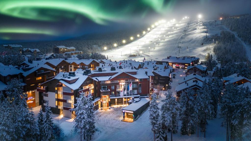 a resort in the snow at night with the northern lights at Break Sokos Hotel Levi in Levi