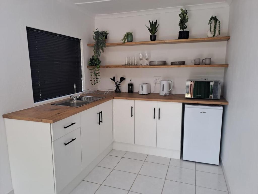 a kitchen with white cabinets and a wooden counter top at 2 On Greeff in Graaff-Reinet