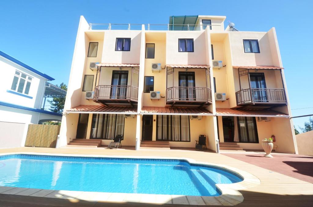 a building with a swimming pool in front of a building at West Sand Holidays LICENSED BY THE TOURISM AUTHORITY 09926 in Flic-en-Flac