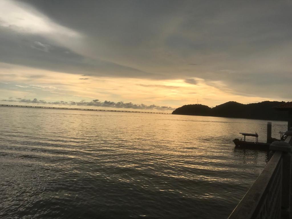 un barco en el agua con una puesta de sol en el fondo en Batu Kawan HS, en Simpang Ampat