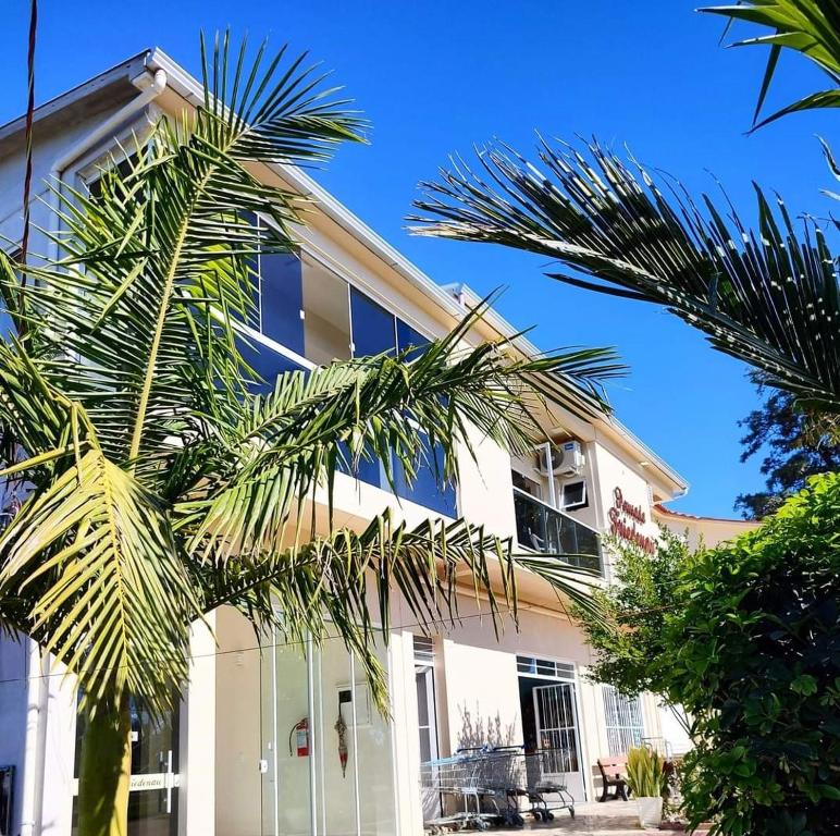 een wit gebouw met palmbomen ervoor bij Hotel Pousada Friedenau 