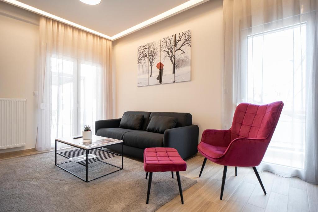 a living room with a black couch and two red chairs at City Palace Trikala in Tríkala