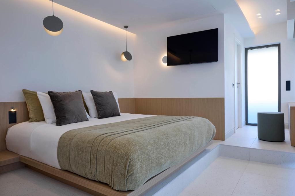 a bedroom with a large bed and a flat screen tv at Twinn Downtown Piraeus in Piraeus