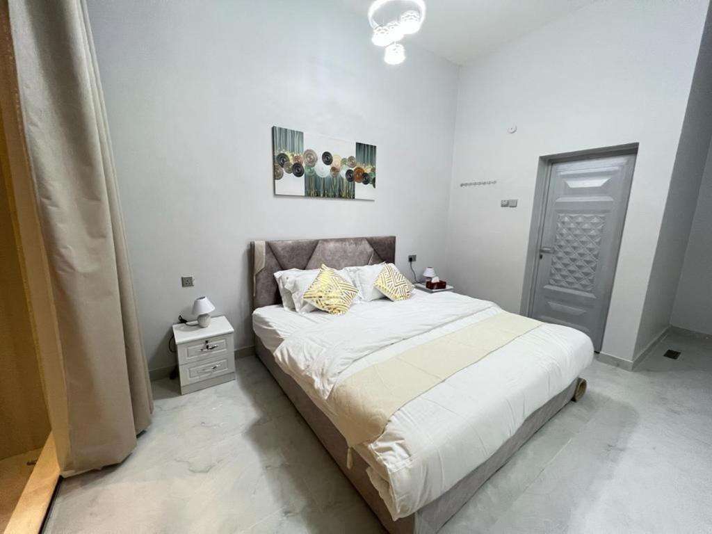 a bedroom with a bed with white sheets and yellow pillows at alsaif camp in Bidiyah