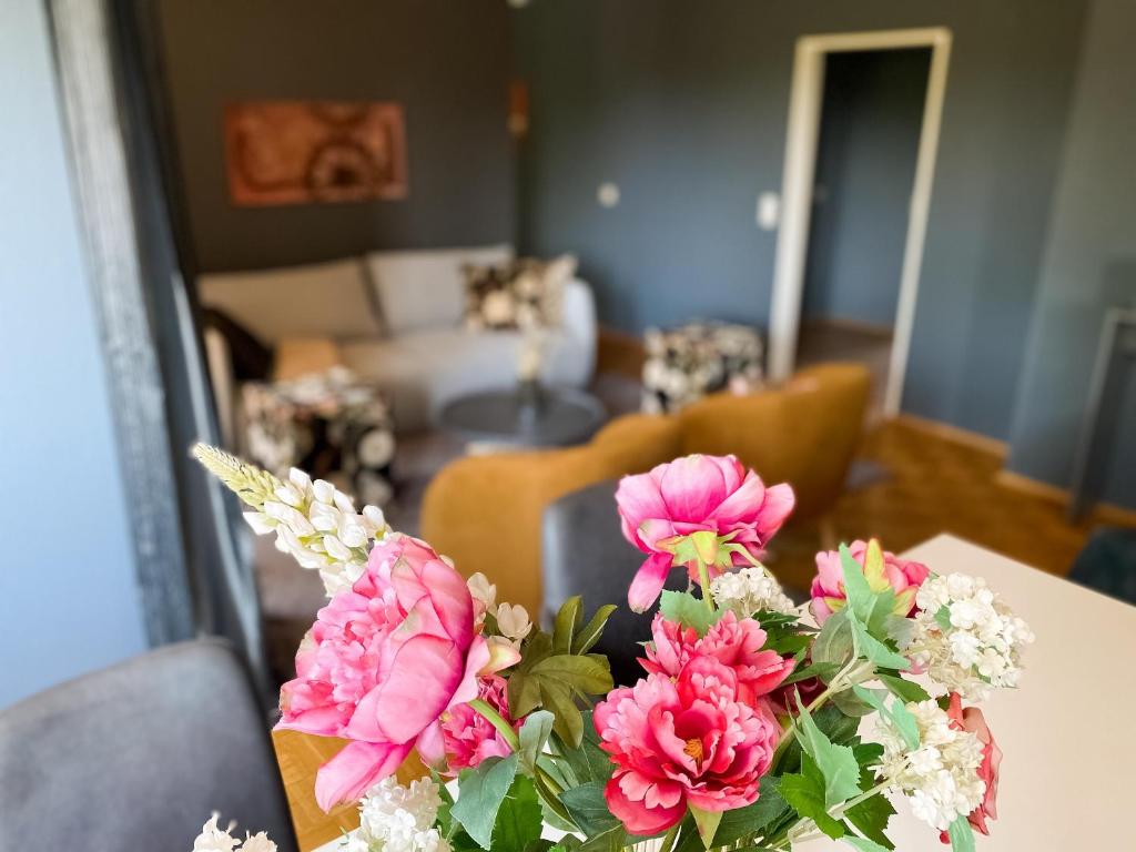 un jarrón de flores rosas sentado en una mesa en Apartment Prinz Ernst August - Zentral - Zimmerprinzen, en Oldenburg