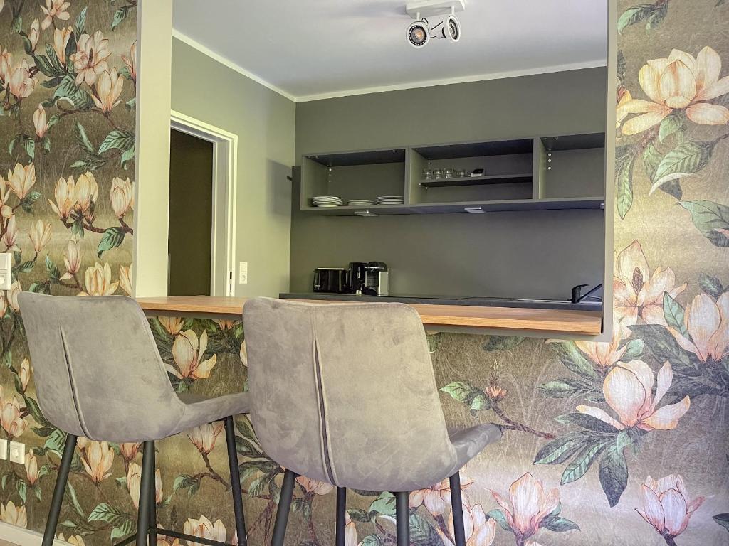 - une cuisine avec 2 chaises et un comptoir fleuri dans l'établissement Apartment Prinz Leopold - Zentral - Zimmerprinzen, à Oldenbourg