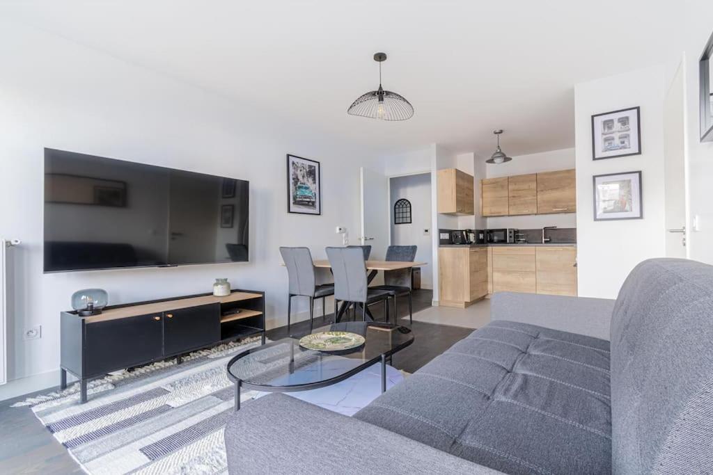 een woonkamer met een bank en een tafel bij Appartement neuf, lumineux & cosy proche La Défense, Neuilly & Paris in Puteaux