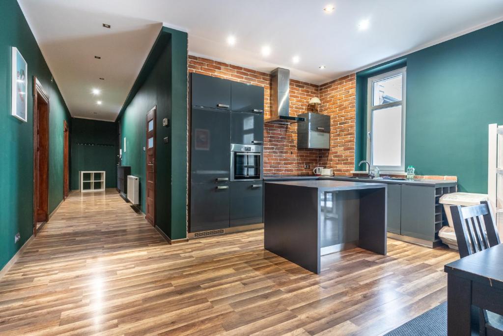 a kitchen with blue walls and a wooden floor at Żwirki i Wigury Comfort Apartment in Katowice