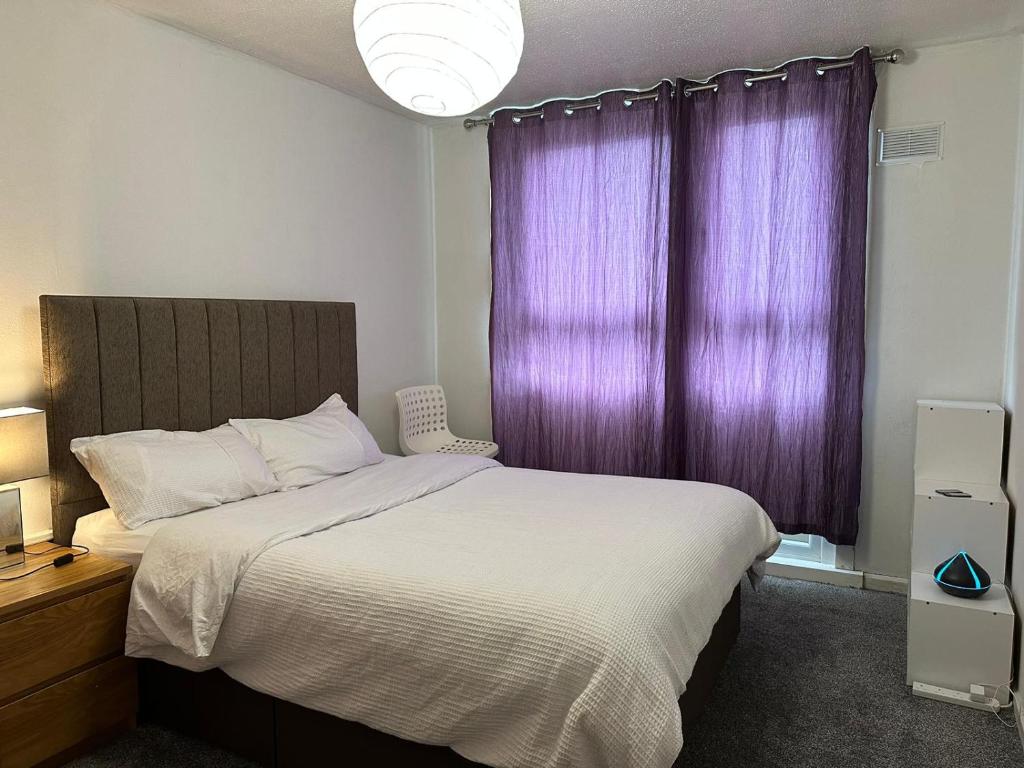 a bedroom with a large bed with purple curtains at Private room in Glasgow City Center in Glasgow