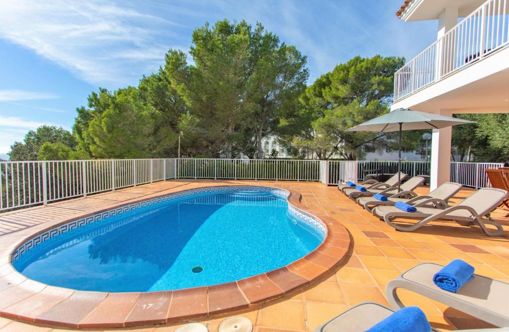 a swimming pool with lounge chairs and an umbrella at Villa Mirador A by Sonne Villas in Cala Galdana