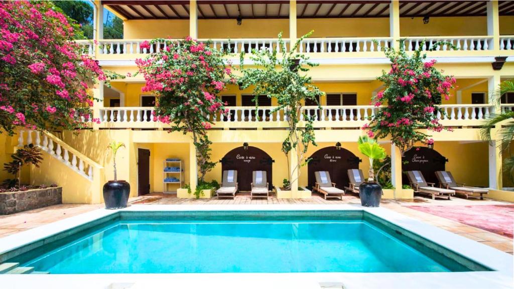 a pool in front of a building with flowers at The Old Gin House Hotel in Oranjestad