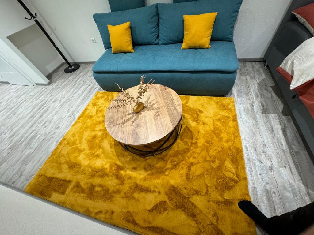 een woonkamer met een blauwe bank en een geel tapijt bij Studio apartman Cuprija in Cazin