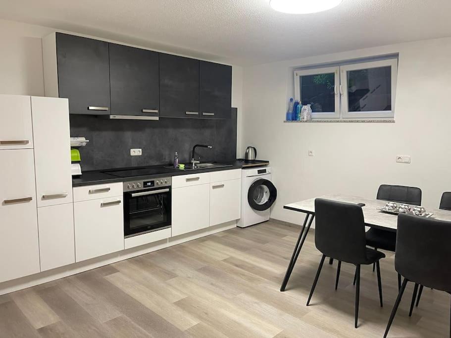 a kitchen with white cabinets and a table with chairs at Monteurwohnung Kassel, 4 Personen in Niestetal