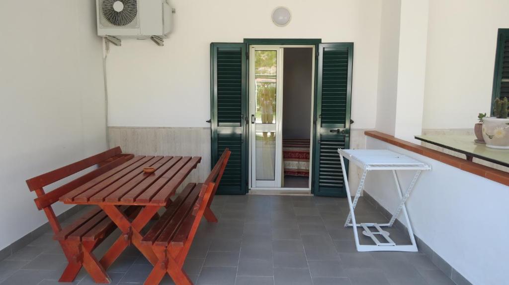 a wooden table and bench in a room with green shutters at Hotel Residence Villa Ascoli in Vieste