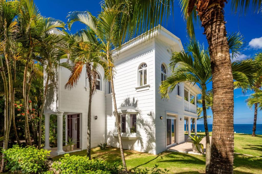 una casa blanca con palmeras frente al océano en Luxury Oceanfront Villa with Amazing Views, en Sosúa