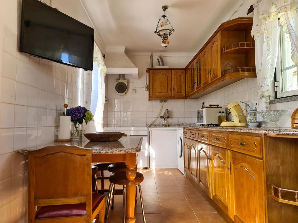 uma cozinha com armários de madeira e uma pequena mesa em Casa Vista da Serra - Covilhã na Covilhã