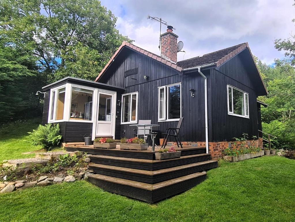 a black tiny house with a porch and stairs at 2 Bed in Blair Atholl 87927 in Bridge of Tilt