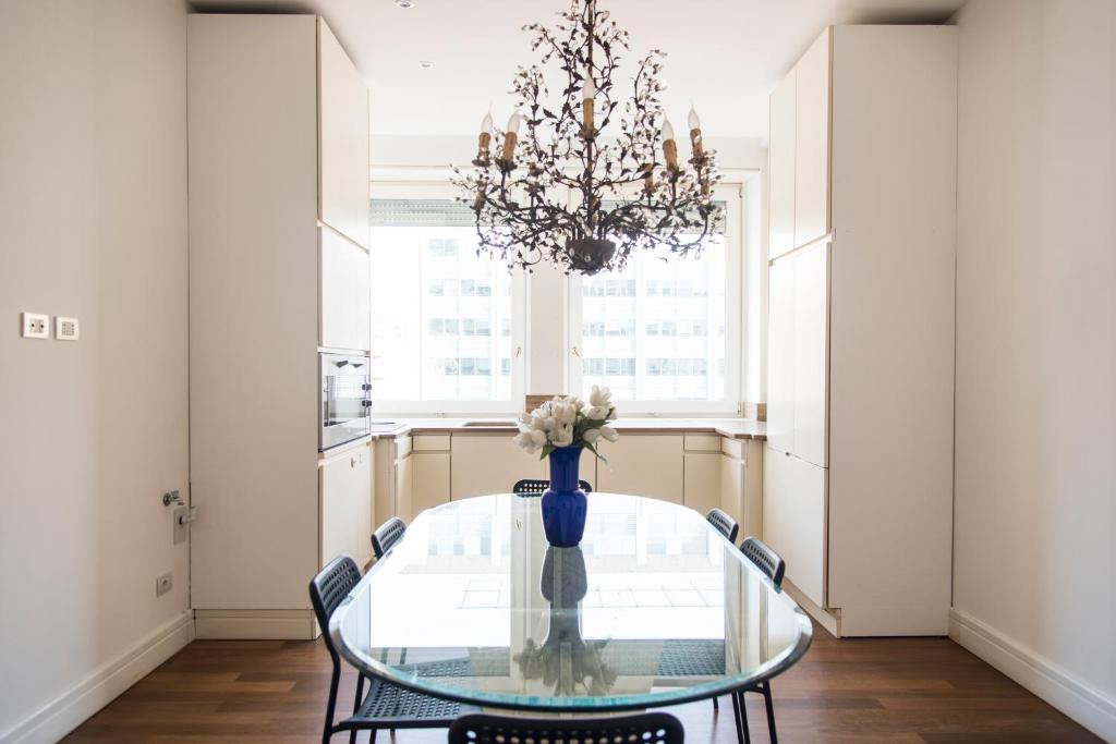 una sala da pranzo con tavolo in vetro e lampadario pendente di Vittore Rooms & Apartment a Milano