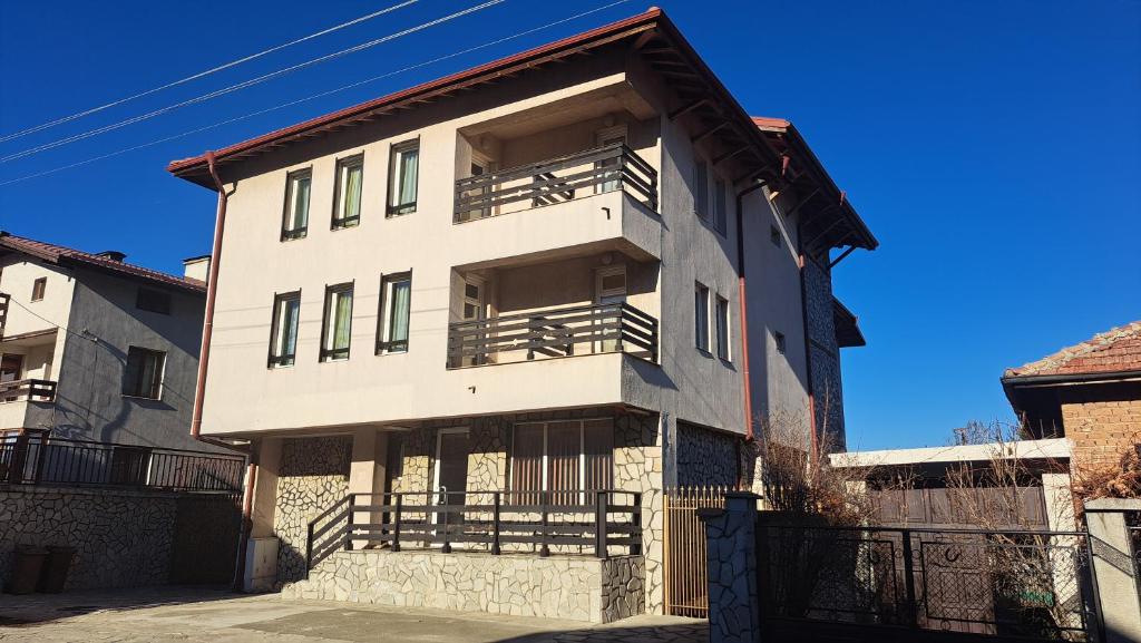 a white building with a balcony on a street at Къща за гости REAL in Bansko