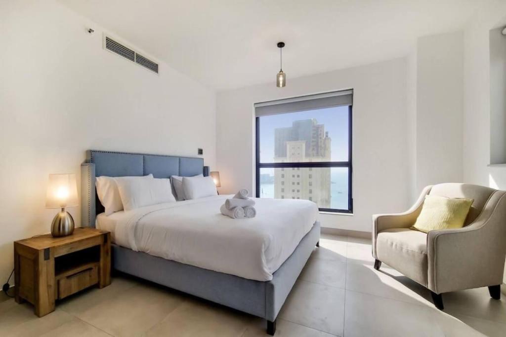 ドバイにあるJbr Sea View Captivating 4-Bed Apartment in Dubaiのベッドルーム(大型ベッド1台、椅子付)