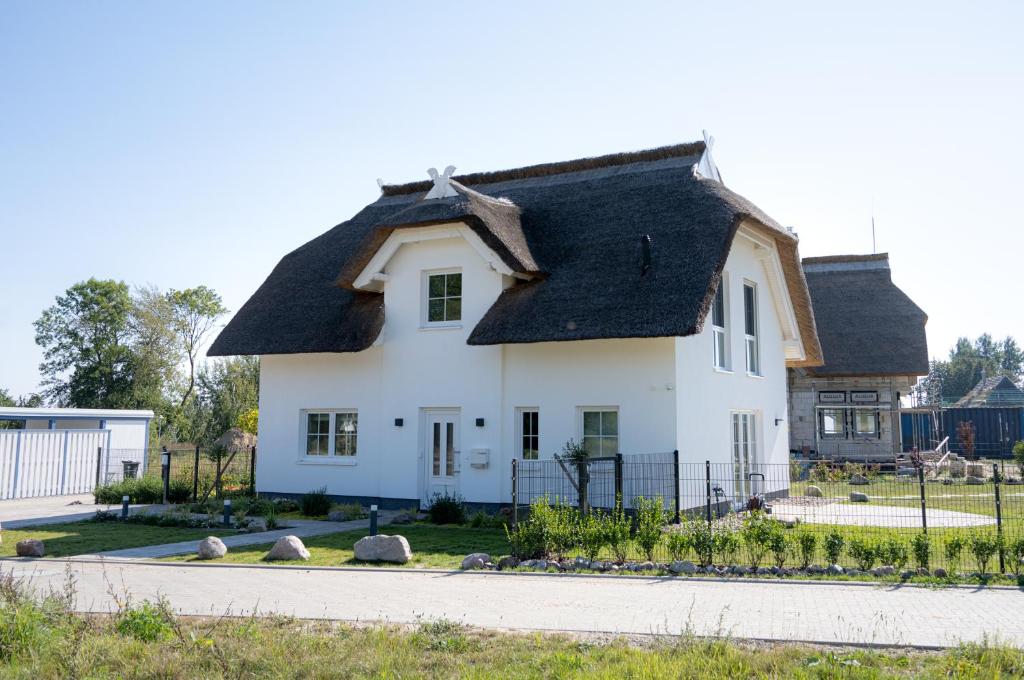 a white house with a black roof at Familienurlaub im Hus in de Sünn in Puddemin