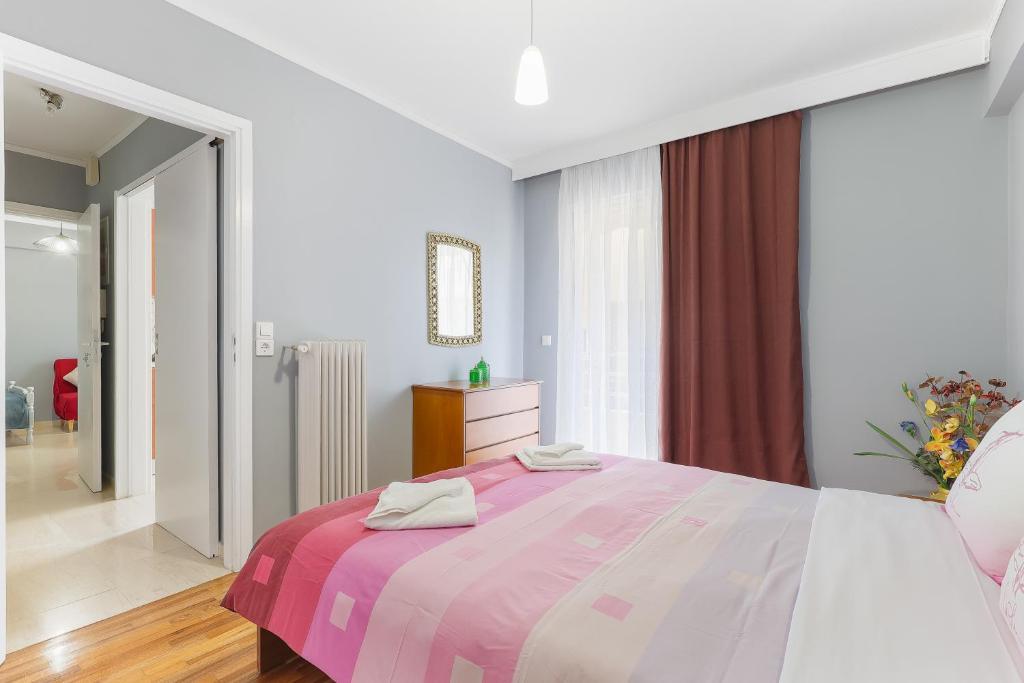 ein Schlafzimmer mit einem großen Bett mit einer rosa Decke in der Unterkunft Thanasis Family Apartment in Athen