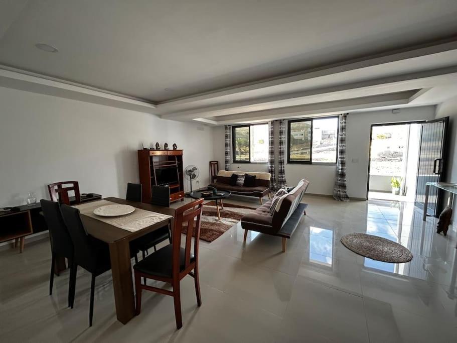 een woonkamer met een tafel en stoelen en een bank bij Modern Apartment in Praia Baixo - 1 min Walking to Beach in Praia Baixo
