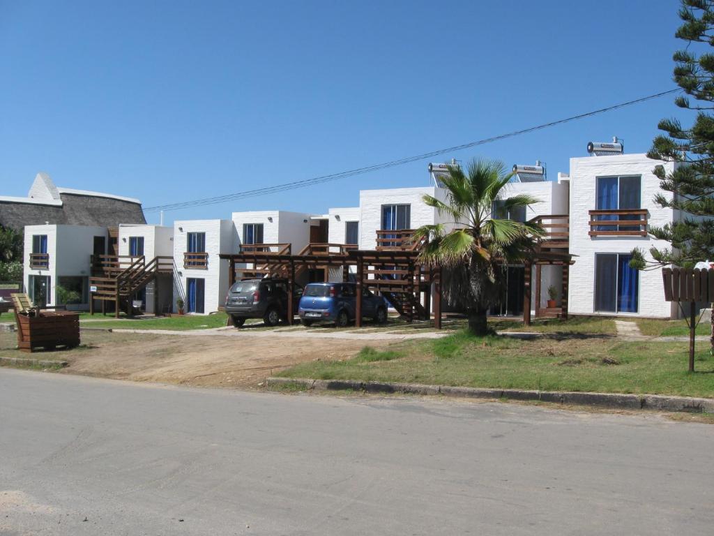 una fila de casas blancas con una palmera delante en Altos de La Balconada, en La Paloma